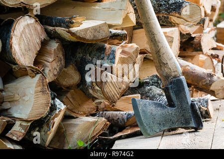 Alte Axt gegen einen angehäuft Stücke von Brennholz Stockfoto