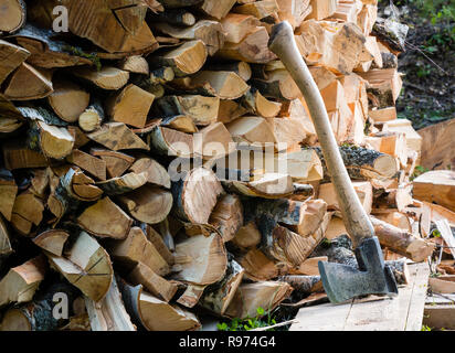 Alte Axt gegen einen angehäuft Stücke von Brennholz Stockfoto