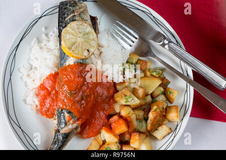 Ofen gebackene Makrelen auf einem Bett aus Reis mit sautierten Kartoffeln und eine Basilikum und Tomatensauce. Stockfoto