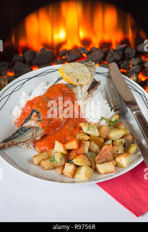 Ofen gebackene Makrelen auf einem Bett aus Reis mit sautierten Kartoffeln und eine Basilikum und Tomatensauce. Stockfoto