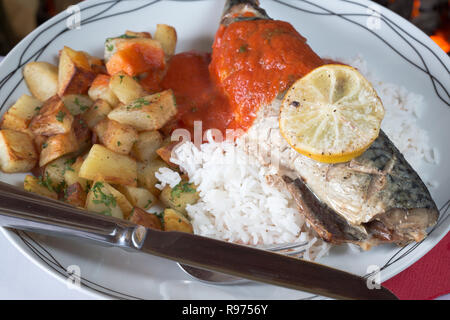 Ofen gebackene Makrelen auf einem Bett aus Reis mit sautierten Kartoffeln und eine Basilikum und Tomatensauce. Stockfoto