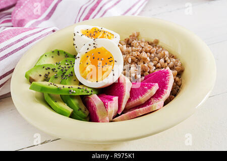 Buchweizen Brei buddha Schüsseln mit Avocado, gekochte Eier und Wassermelone Rettich auf weißer Tisch. Gesundes Frühstück. Stockfoto