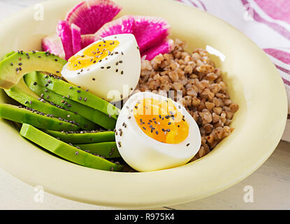 Buchweizen Brei buddha Schüsseln mit Avocado, gekochte Eier und Wassermelone Rettich auf weißer Tisch. Gesundes Frühstück. Stockfoto