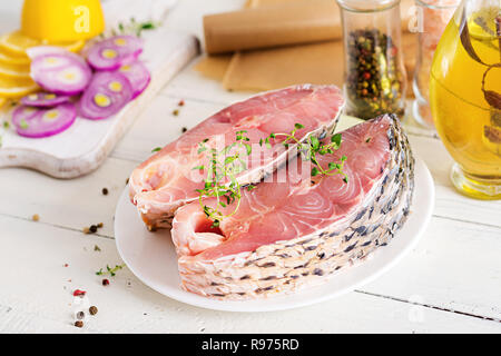 Rohen Steak von karpfen fisch mit Zitrone und Thymian auf weißem Holz- Hintergrund. Die Zubereitung von Fisch zum Braten in Pergamentpapier. Diätmenü. Stockfoto