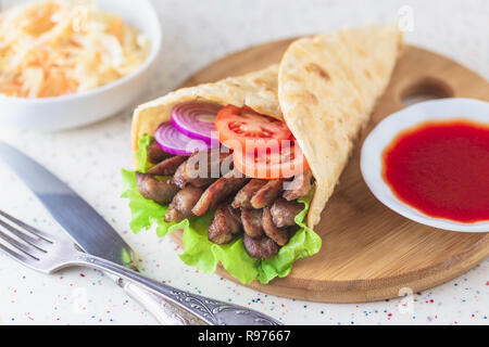Handgefertigte Döner liegt auf dem weißen Tisch aus Kunststein. Shawarma auf dem hölzernen Schneidebrett mit Hühnerfleisch. Stockfoto