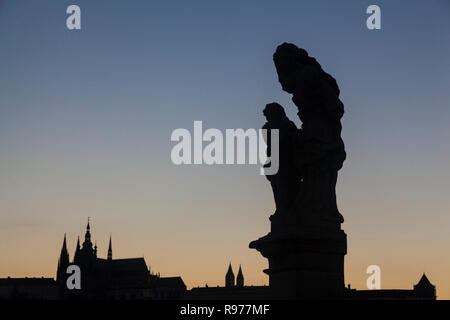 Statue auf der Karlsbrücke und der Prager Burg im Hintergrund Stockfoto