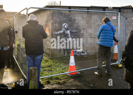 Umzäunung schützt ein Kunstwerk von Street Artist Banksy, die auf eine Garage Wand in Taibach, Port Talbot, South Wales erschienen ist. Das Bild erschien über Nacht und zeigt ein Kind, das in den fallenden Asche und Rauch von einem Feuer in einem fort. Stockfoto