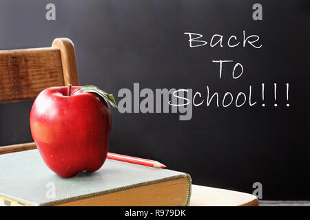 Schule Bücher mit Apple sitzt auf einem Schüler Schreibtisch vor einem Chalk board. Stockfoto
