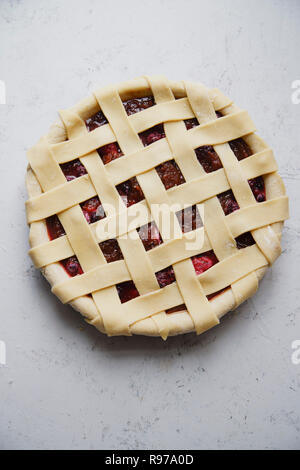 Ungekocht berry Pie mit einem Gitter Dekoration oben auf. Konkreten Hintergrund, Kochen. Stockfoto