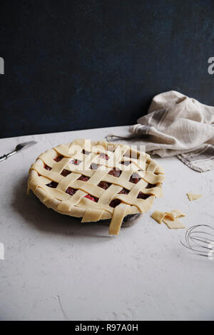 Ungekocht berry Pie mit einem Gitter Dekoration oben auf. Konkreten Hintergrund, Kochen. Stockfoto