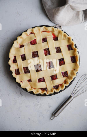 Ungekocht berry Pie mit einem Gitter Dekoration oben auf. Konkreten Hintergrund, Kochen. Stockfoto