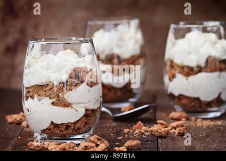 Drei Gläser zerbröckelt Chocolate Chip Cookies und Käsekuchen parfaits gegen eine rustikale Hintergrund. Extrem flache Tiefenschärfe mit selektiven fo Stockfoto