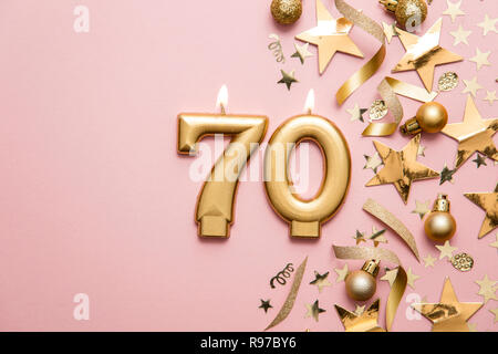 Nummer 70 gold Feier Kerze auf Sterne und Glitzer Hintergrund Stockfoto