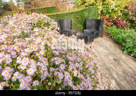 Zwei schwarze Design Garten Stühle und Tisch neben einem blühenden Grenze in einem Garten irgendwo in den Niederlanden Stockfoto