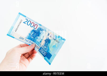 Weibliche Hand hält 2000 russische Rubel Bill auf weißem Hintergrund mit Kopie Raum, neue russische Banknote Stockfoto