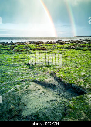 Regenbogen über der berühmten Fußabdrücke von Dinosauriern zu einem corran Strand von staffin auf die Isle of Skye - Schottland Stockfoto