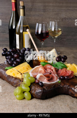 Antipasto catering Plattenteller mit ruckartiger Speck, Schinken, Salami, Käse und Trauben auf einem hölzernen Hintergrund Stockfoto