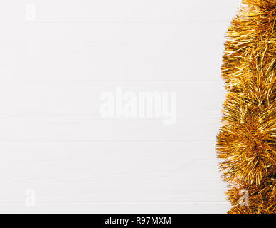 Flach Zusammensetzung der goldene Weihnachten lametta Girlande auf weissem Holztisch mit Kopie Raum, Ansicht von oben. Stockfoto