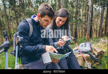 Paar tun Trekking sitzen auf der Suche mobile und Karte Stockfoto