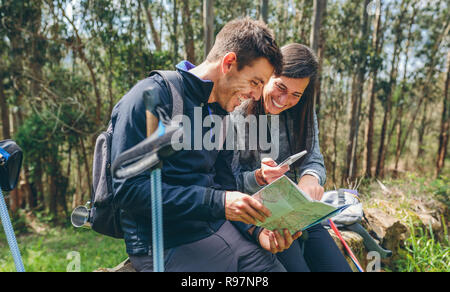 Paar tun Trekking sitzen auf der Suche mobile und Karte Stockfoto