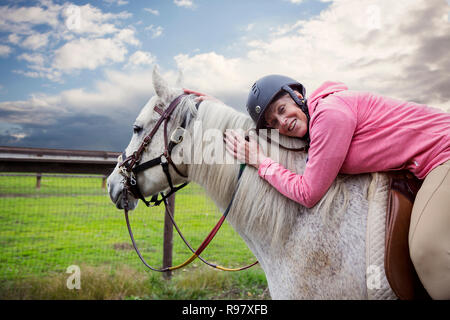 Senior liegende Frau auf dem Pferderücken Stockfoto