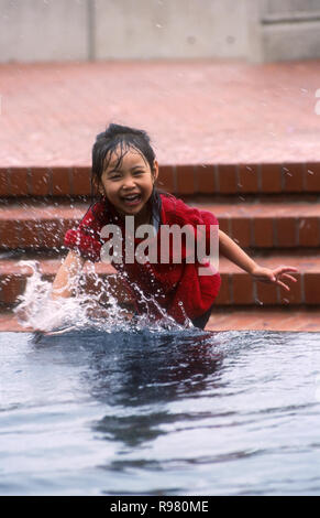 Eine junge ASIATIN ABKÜHLUNG UND SPASS IN EINEM Springbrunnen und Teich in der Stadt Sydney, New South Wales, Australien Stockfoto