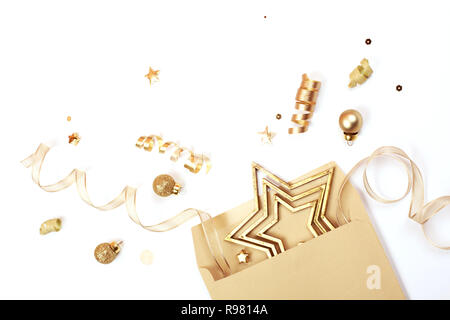 Golden Weihnachtsschmuck erweitert aus dem Geschenk Umschlag. Sterne, was glänzt, Kugeln und Bänder sind auf weißem Hintergrund. Gruß an Weihnachten Konzept. Stockfoto
