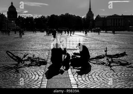 Radfahrer sitzen in Palace Square, St. Petersburg, Russland, die neben ihrer Fahrräder. Schwarzweißbild schoß contre-jour. Stockfoto