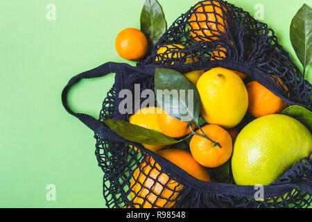 Schwarzer Stoffbeutel voller bunter Zitrusfrüchte. Gesunde Ernährung und null Abfall Konzept. Stockfoto