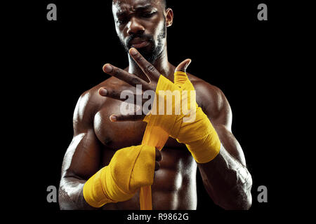 Afro-amerikanische Boxer wickelt sich die Hände mit gelben Bandage Stockfoto