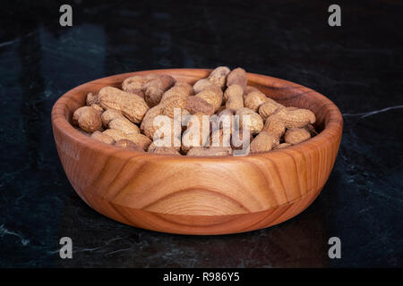 Erdnüsse in einem Holz Schüssel und auf Marmor tisch Stockfoto