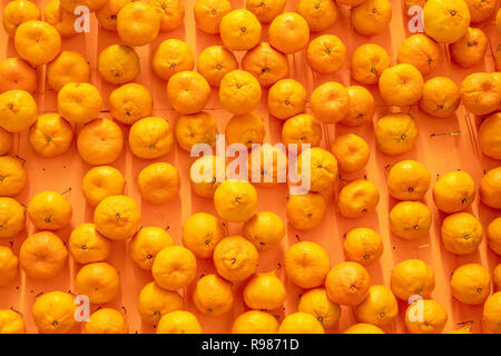 Eine Menge Mandarinen verstreut auf eine Orange. Essen Hintergrund. Close-up. Stockfoto