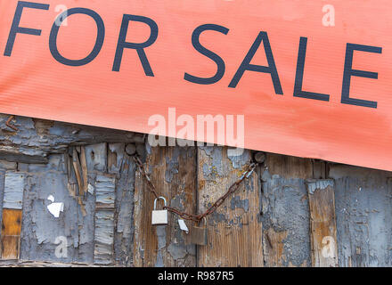 Alte verwitterte Tür. Alte Tür mit Banner für den Verkauf auf Top mit Kette und Vorhängeschloss gesichert korrodiert. Stock Bild. Stockfoto