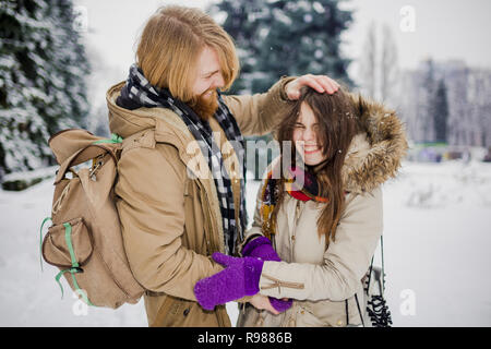 Datum des jungen Paares im Winter. Jungen kaukasischen Mann mit Bart und langen Haaren Aprilscherze kid snow Schneebälle mit einer Frau, winter spiele Va Stockfoto