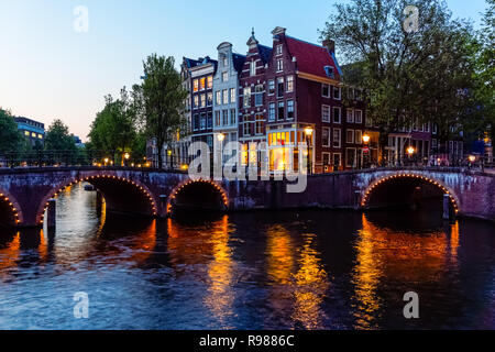 Traditionelle niederländische Stadthäuser und beleuchtete Brücken am Keizersgracht-Kanal in Amsterdam, Niederlande, Europa Stockfoto