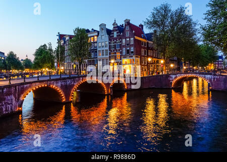 Traditionelle niederländische Stadthäuser und beleuchtete Brücken am Keizersgracht-Kanal in Amsterdam, Niederlande, Europa Stockfoto