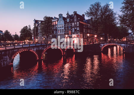 Traditionelle niederländische Stadthäuser und beleuchtete Brücken am Keizersgracht-Kanal in Amsterdam, Niederlande, Europa Stockfoto