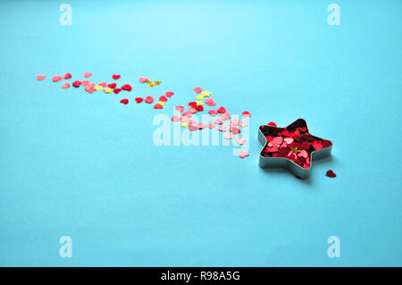 Sternförmige Box mit roten Herzen auf blauem Hintergrund. Minimalistischer Stil. Stockfoto
