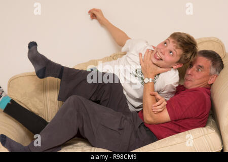 Großvater oder Vater kämpfen, spielen, kämpfen, Ringen, spielen rauh, mit Sohn oder Enkel, Jugend, zwölf Jahre alt -, auf dem Sofa Sofa, Spaß zu haben. Stockfoto