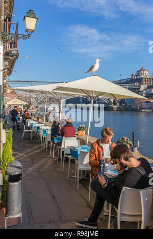 Porto, Portugal - Januar 19, 2018: Nicht identifizierte Personen in Outdoor Cafe am Ufer des Flusses Douro mit einem schönen Blick auf Ponte Dom Luis Brücke Stockfoto