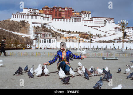 Lhasa, Tibet autonomen Region, China: Eine junge Frau Feeds die Tauben im Potala Platz vor dem Potala Palast. Zuerst im Jahre 1645 erbaut durch das 5. Stockfoto