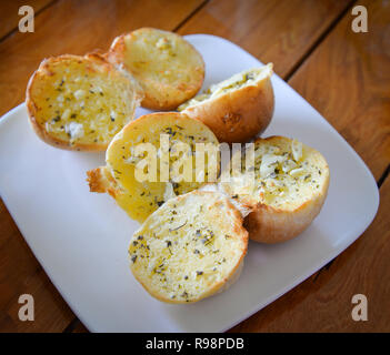 Frühstück Brot am Tisch / Essen oder Snack gebackenes Brot rund die Hälfte mit Gewürzen und Knoblauch auf weiße Platte Holztisch Hintergrund Frühstück im Mor Stockfoto