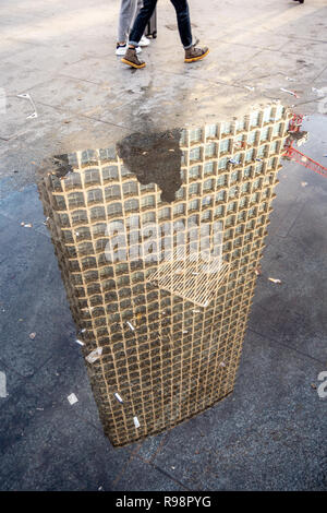 Reflexion von Menschen zu Fuß in der Nähe von einem regen Pfütze und kopfüber Mittelpunkt eines 33-stöckigen Büroturm Block in der Nähe der Tottenham Court Road und die Oxford Street Stockfoto