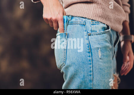 Mädchen setzt Geld in die Tasche der Jeans zurück Papiergeld 200 und 2000 Rubel. Stockfoto