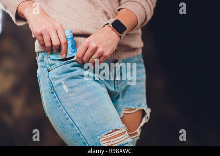 Mädchen setzt Geld in die Tasche der Jeans zurück Papiergeld 200 und 2000 Rubel. Stockfoto