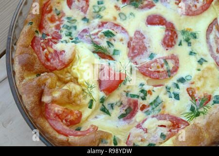 Fragment einer üppigen Omelett mit einem rötlichen Kruste, Scheiben der roten Tomaten, grüne Zwiebeln und Dill verlässt. Stockfoto