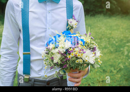 Bräutigam hält einen schönen Blumenstrauß in der Hand. Hochzeit im rustikalen Stil. Stockfoto