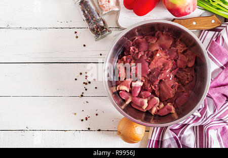 Rohes Huhn Leber in der Schüssel auf weißem Holz- Hintergrund. Lebensmittelzutat. Ansicht von oben Stockfoto