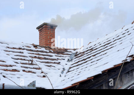 Rauchen Schornstein auf ein traditionelles Haus in einer ländlichen ungarischen Dorf im Schnee von einem frischen Schneesturm zala Ungarn Stockfoto