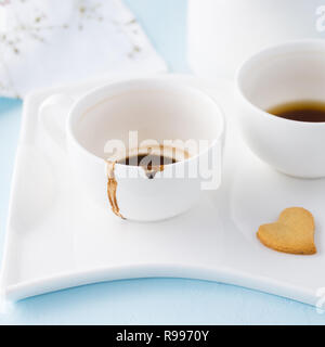 Zwei leere Tassen Kaffee und herzförmige Plätzchen auf ein Fach. Stockfoto